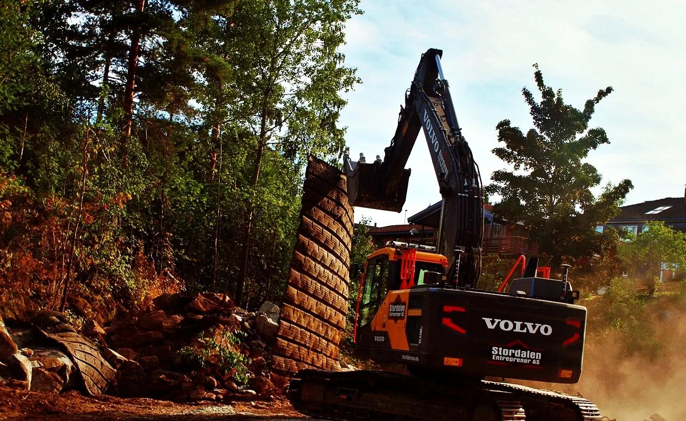 Volvo beltegraver fra Stordalen graver i skrått terreng mellom trærne