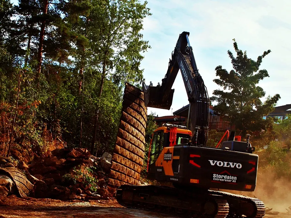 Volvo beltegraver fra Stordalen graver i skrått terreng mellom trærne